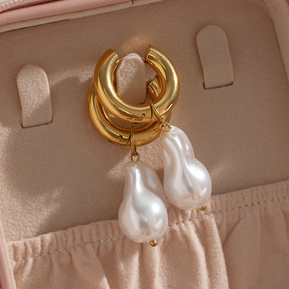 Gold earrings with pearl drops on a pink jewelry box