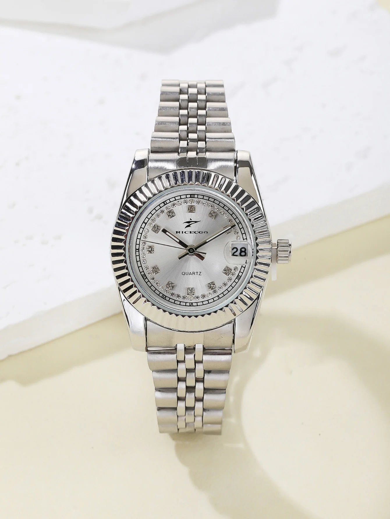 A women's quartz wristwatch with a textured bezel design and diamond studded dial decoration, equipped with date display functio
